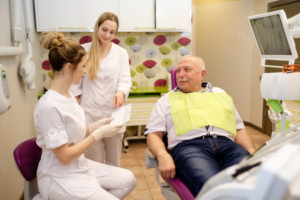 a dental assistant helping a senior patient